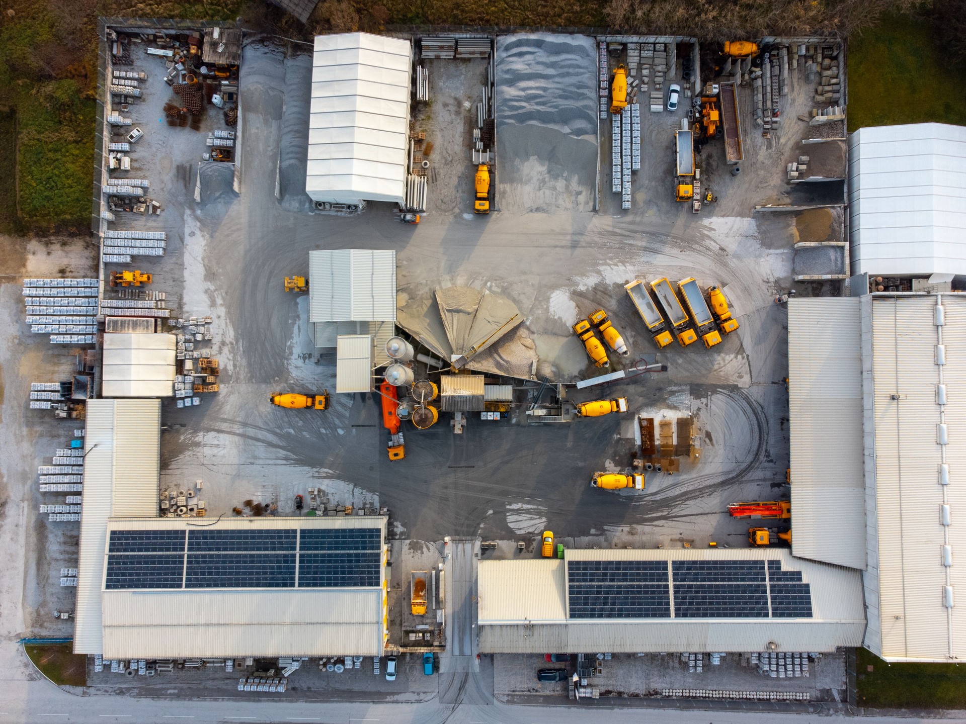 Construction and concrete factory lot, solar panels on the rooftop and yellow cement trucks on site