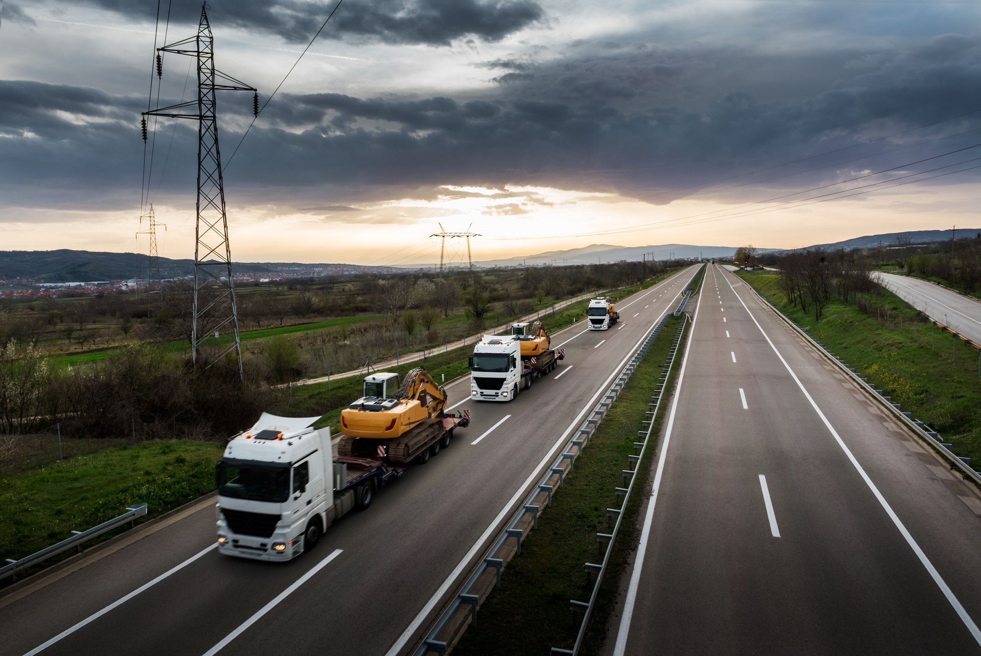 Tow Trucks in a row carrying Construction Machines Excavators