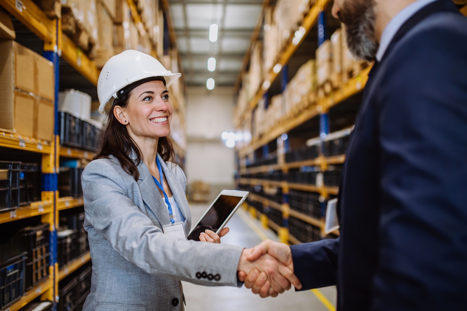 Managers in suits shaking hands in warehouse.