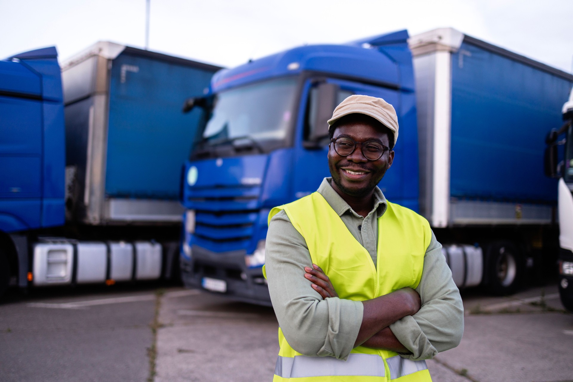 Truck driver in reflective clothing standing on parking lot.